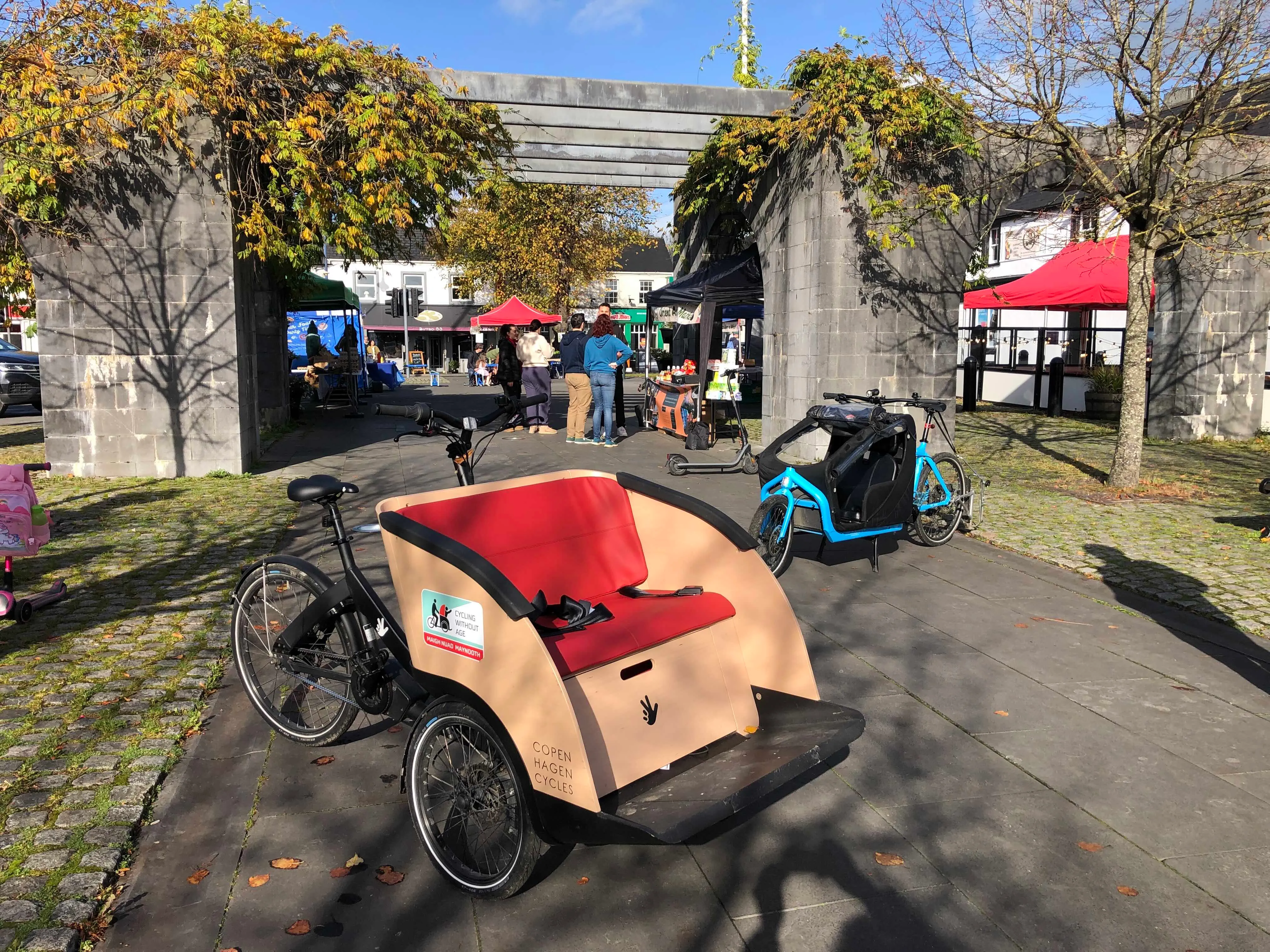 The Maynooth Cycling Campaign trishaw, with its red bench seat, at the Saturday market in Maynooth town square.