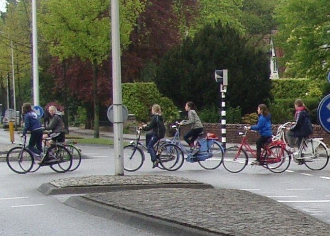 Several children cycling together across a junction on their way to school