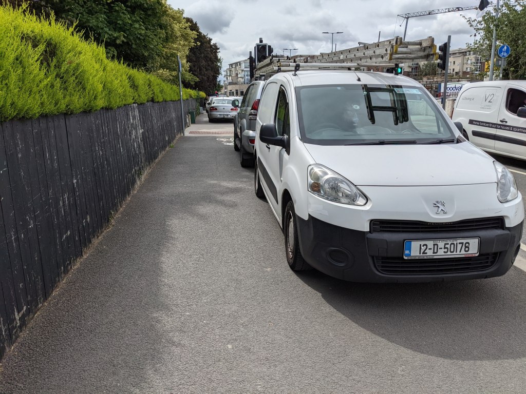 A white van and cars parked on the footpath beside the Moyglare Road, blocking the path for pedestrians