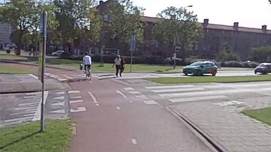 A cyclist and pedestrian cross a Dutch roundabout in ’s-Hertogenbosch as a car waits, giving them priority