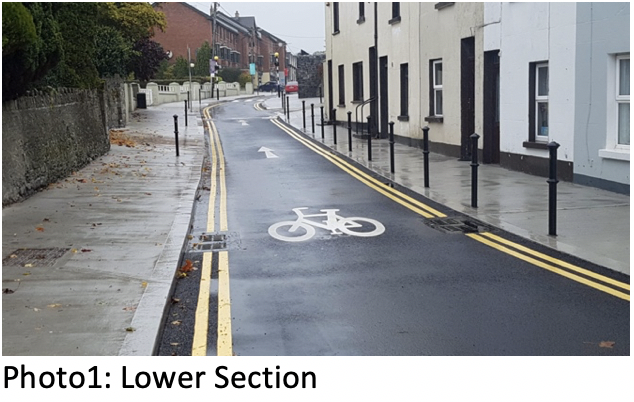 Photo 1, Lower Section: widened footpath and bollards on Cleamore Road, with a cycle symbol painted on the road
