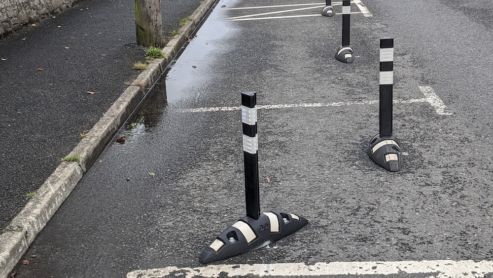 Black bollards and white ‘orca’ plastic lane separators along a wet cycle lane on the Dublin Road, Maynooth