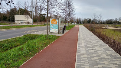 A wide red-surfaced cycle track beside a separate paved footpath in Cambridge’s Eddington development