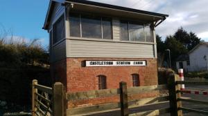 Restored brick-and-timber railway signal box labelled ‘Castletown Station Cabin’ beside the greenway.