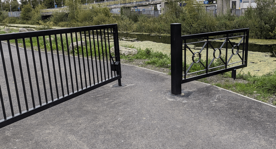 Narrow metal barrier gates across a greenway path on the Royal Canal, restricting cycle access