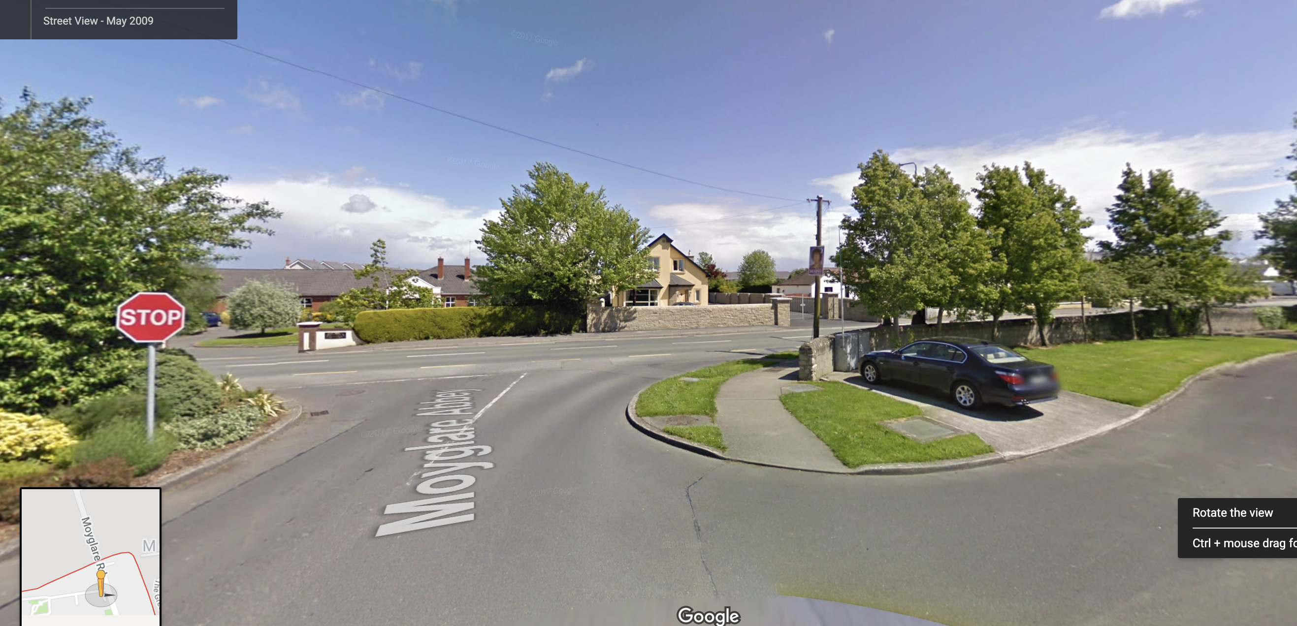 Google Street View of the wide road junction at the Moyglare Abbey estate entrance, with a stop sign and houses